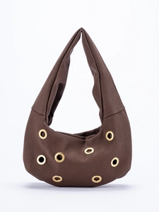 Detailed macro view of dark brown suede shoulder bag with gold metal grommet ornaments
