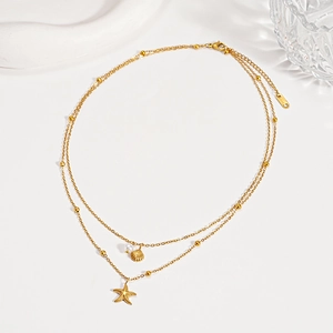 Close-up of golden layered necklace featuring starfish, shell pendants and a pearl detail