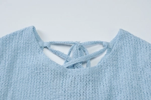 Dettaglio del top in maglia traforata azzurro con intreccio posteriore e lacci regolabili