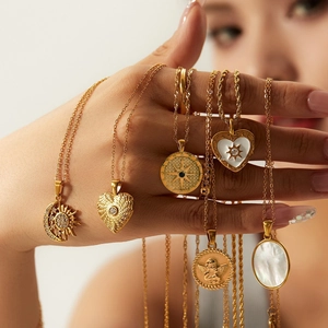 Detail of bohemian gold necklaces with shell heart, sun, and angel relief pendants