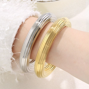 Bracelets joncs évidés en acier inoxydable plaqué or 18k et argent portés par un mannequin