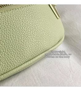 Macro shot of light green lychee grain leather texture and metallic zipper on cross-body bag
