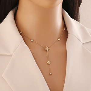 Élégant collier en Y doré avec trèfle et zircons blancs porté par un mannequin en veste