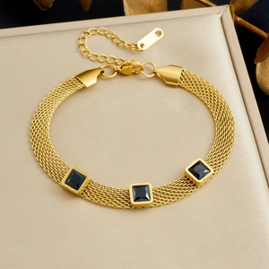 Detail of gold mesh chain bracelet with three square black gemstones on display