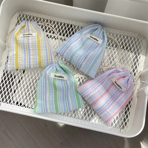 Detail of four colorful seersucker drawstring pouches with striped texture and cotton cords