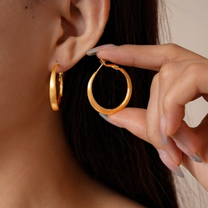 Close-up of 18k gold plated brushed metal hoop earrings worn with elegant matte finish