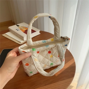 Close-up of quilted cotton handbag featuring colorful polka dots and secure zipper closure