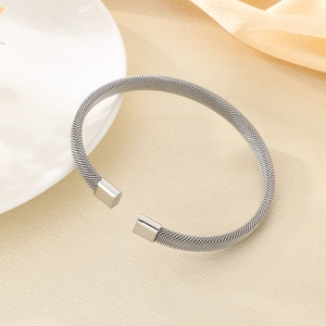 Vista macro di un bracciale rigido a rete intrecciata argento con apertura regolabile