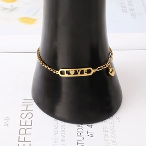 Détail d'un bracelet cœur en acier titane doré avec découpe LOVE sur un support noir