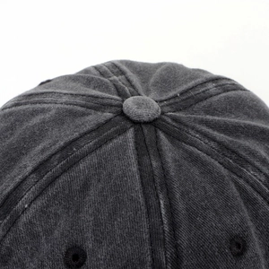 Macro shot of washed cotton texture and reinforced top button on dark gray baseball cap