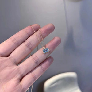 Detailed view of rectangle cut light blue crystal pendant with delicate gold chain
