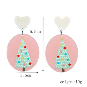 Détail de boucles d'oreilles roses avec sapin de Noël vert et pendentif coeur blanc