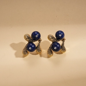 Close-up of vintage gold earrings with blue bead accents and white micro-rhinestones