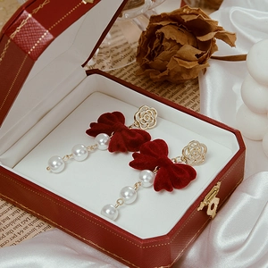 Detail of red velvet bow earrings with pearls and golden rose buckle in a gift box