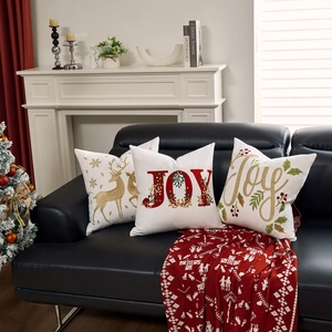 Detailed embroidery of gold reindeer and Joy lettering on white Christmas cushion covers