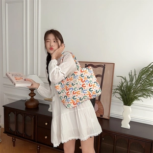 Quilted tote bag in beige with colorful C pattern in a minimalist French interior scene