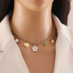 Golden Cuban chain necklace with pearl heart and floral charms on a white suit model