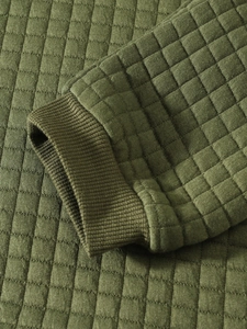 Macro shot of army green waffle knit fabric texture and ribbed cuffs on men's sweatshirt