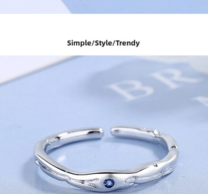 Détail macro d'une bague argentée à texture ondulée ornée d'un zircon bleu rond