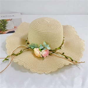 Detailed view of beige straw hat with hollow petal wavy brim and floral garland