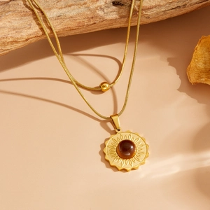 Détail d'un collier double rangée en or avec pendentif tournesol et pierre œil-de-chat