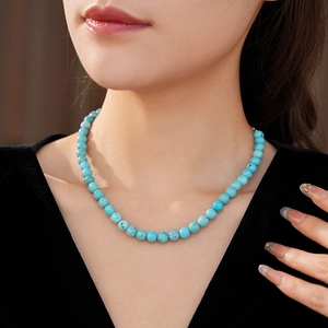 Close-up of turquoise beaded necklace on model highlighting vibrant blue beads and texture
