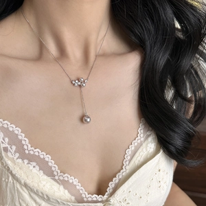 Detailed shot of a minimalist pearl necklace with zircon pendant worn by a model