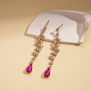 Detailed view of long gold tassel earrings with rose red teardrop gems and rhinestones
