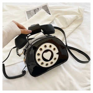 Close-up of retro black patent leather telephone bag with dial pad and receiver handle