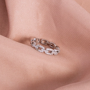Close-up of silver hollow heart chain ring with white zircon pave on satin fabric