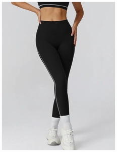 Detail of high-waisted black yoga leggings with contrast white side stripes for leg shaping