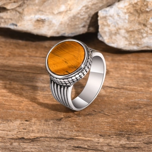 Detailed shot of men's tiger eye ring with vintage silver-tone metal on natural wood