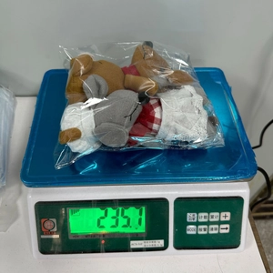 Detail view of plush bear and rabbit toys in festive plaid outfits on digital scales