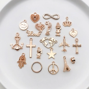 Collection of rose gold DIY jewelry pendants including heart and crown shapes on a white plate