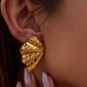 Close-up of golden irregular wavy textured pearl earrings on model for a luxury look