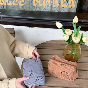 Detail view of vintage corduroy makeup bags with smiling faces on a wooden table