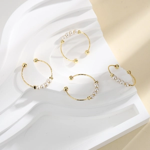 Golden twisted open ring with four white pearls on a professional display background