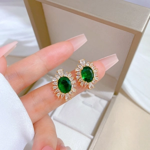 Close-up of gold-plated earring with green oval gem and micro-pave cubic zirconia