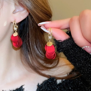 Close-up of red matte petal tassel earrings with golden metal accents and zircon inlay