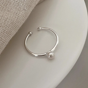Minimalist S925 sterling silver open ring with a small white freshwater pearl on a ceramic tray