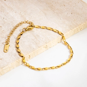 Detailed macro view of gold plated stainless steel bracelet with olive links on marble