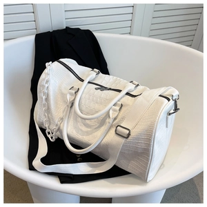 Detailed view of white crocodile pattern travel duffel bag with wide textile shoulder strap