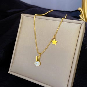 Macro detail of gold-plated rabbit and star pendant on a delicate bead chain necklace