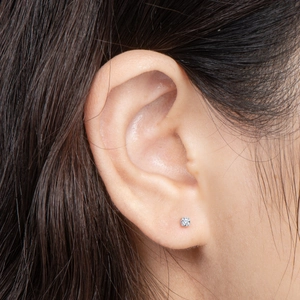 Close-up of a 925 silver four-prong moissanite stud earring worn on the earlobe