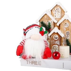Lighted Christmas Rudolf gnome plush doll on white book with festive home decor background