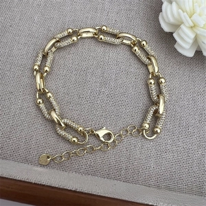 Detail of 18K gold-plated U-shaped link bracelet featuring pave set white zircon stones