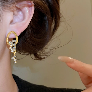 Close-up of elegant gold tassel earrings with zircon crystals worn by a model