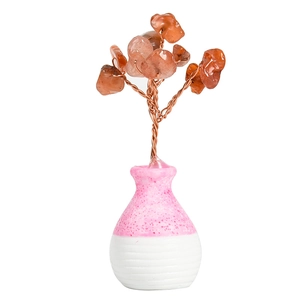 Natural orange crystal gemstone tree in a pink and white ceramic vase for home decor