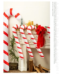 Giant red and white inflatable candy canes set against a festive Christmas fireplace