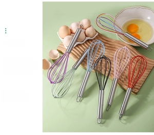 Macro view of colorful silicone whisks with stainless steel handles on wooden board